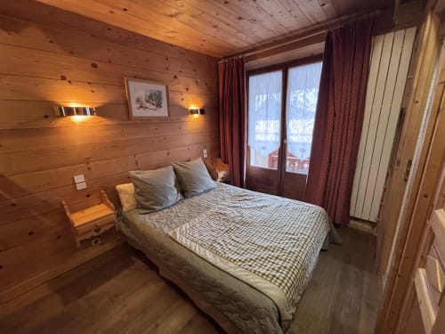 Chambre chaleureuse en bois chez Francine, lit queen-size, vue sur les montagnes par portes vitrées, éclairage doux et charme alpin