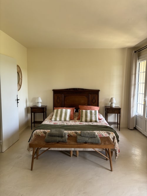 Chambre Verveine au Mas des Vignes avec lit en bois, oreillers rayés et balcon avec vue sur le jardin à Rochegude