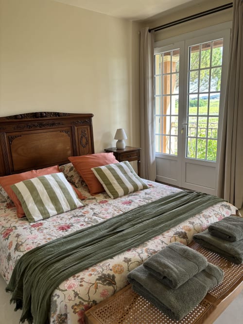 Chambre Verveine au Mas des Vignes avec vue jardin, lit en bois, oreillers rayés et portes-fenêtres à Rochegude