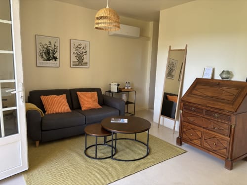 Chambre Verveine à la Maison d'hôtes Le Mas des Vignes, Rochegude - canapé noir avec coussins orange, tables basses rondes, en bois