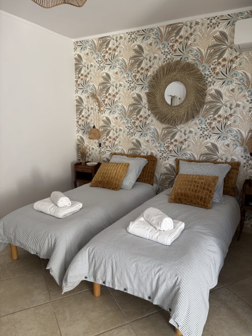 Lits jumeaux aux draps rayés et oreillers dorés dans la chambre Jasmin du Mas des Vignes à Rochegude, avec motifs botaniques