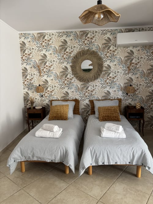 Deux lits jumeaux dans la chambre Jasmin de la Maison d'hôtes Le Mas des Vignes à Rochegude, avec papier peint fleuri et vue sur le jardin