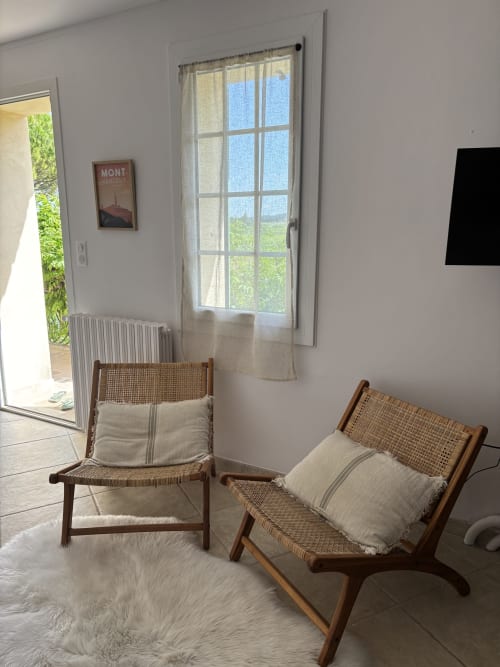 Chambre lumineuse avec chaises tressées, coussins crème et vue sur le jardin par les portes-fenêtres du Mas des Vignes à Rochegude