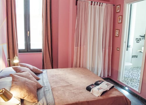 Elegante camera da letto presso LH51 Rooms a Napoli con pareti rosa, tende multistrato e accesso al bagno privato