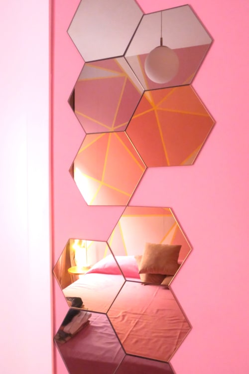 Installazione di specchi esagonali sulla parete in camera dalle tonalità rosa presso LH51 Naples B&B, che riflettono la calda illuminazione interna