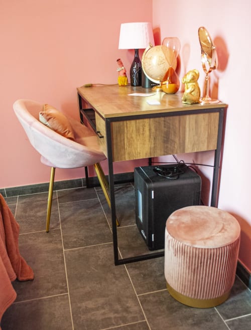 Spazio di lavoro moderno nella Stanza di Pulcinella presso LH51 Napoli: scrivania in legno con lampada bianca, sedia in velluto rosa, accenti in oro e