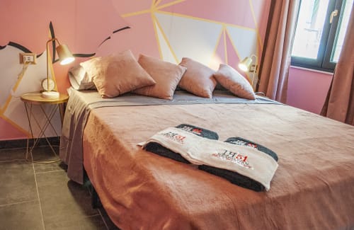 La camera Pulcinella presso LH51 Rooms and Apartments a Napoli dispone di un letto con cuscini corallo, decorazioni geometriche dorate alle pareti e