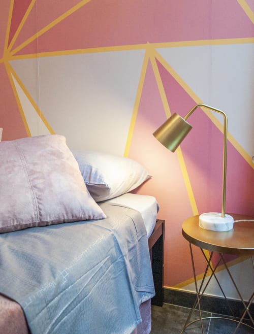 Camera moderna presso LH51 Rooms a Napoli con arte geometrica colorata alle pareti, letto con cuscini e lampada da tavolo in ottone