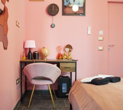 Camera di Pulcinella all'LH51 Napoli: camera rosa con scrivania, sedia, orologio e letto con indumenti neri