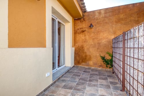 Patio terrace at Finques Garcia Enrich hotel in Palafrugell with terracotta walls, tiled flooring, and metal fence gate.