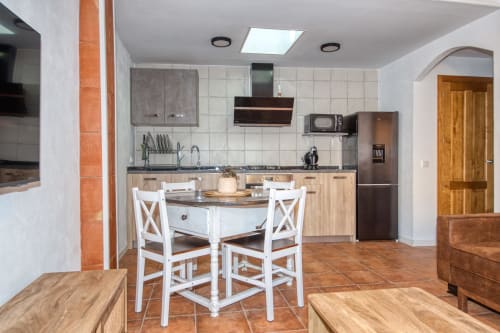 Modern kitchen with dining area at Finques Garcia Enrich hotel in Palafrugell, featuring white chairs and stainless steel