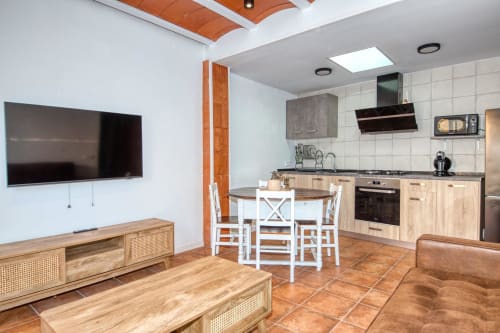 Modern open-plan kitchen and living area at Finques Garcia Enrich in Palafrugell with dining table, TV, and wooden
