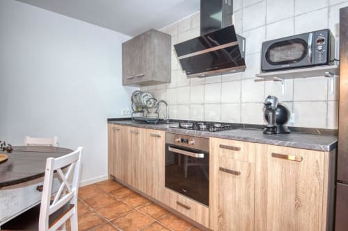 Modern kitchen at Finques Garcia Enrich, Palafrugell with wooden cabinets, gas stove, and dining area