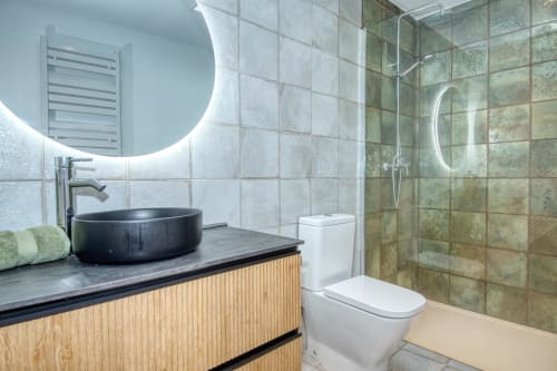 Modern bathroom at Finques Garcia Enrich hotel in Palafrugell with black vessel sink, illuminated mirror, and walk-in shower