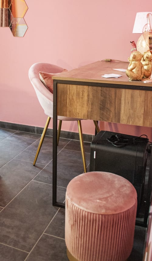 Spazio di lavoro moderno presso LH51 Rooms a Napoli con scrivania in legno, sedia in velluto rosa, dettagli dorati e ceramiche decorative