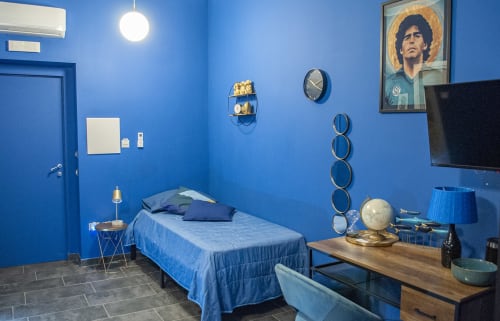 Camera da letto blu vivace presso LH51 Rooms a Napoli con letto singolo, scrivania e quadro ritratto