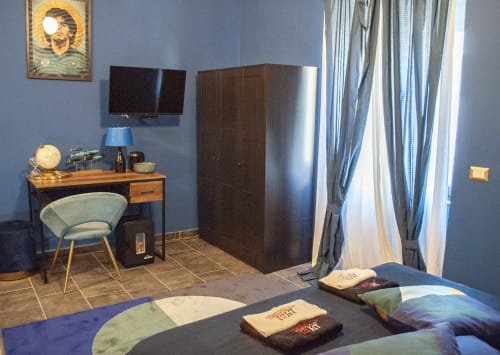 Camera Partenope presso LH51 a Napoli: moderna camera da letto con pareti blu, scrivania, TV, armadio e biancheria con motivi