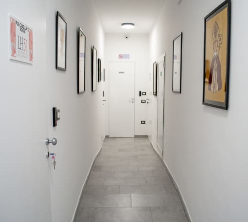 Corridoio moderno delle LH51 Rooms a Napoli con opere d'arte incorniciate, pavimentazione in piastrelle grigie e porte bianche