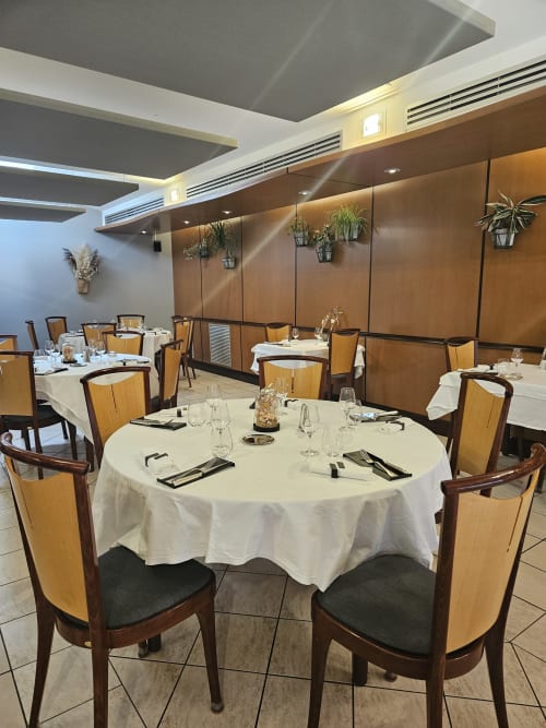 Salle à manger élégante de La Route d'Argent à Bozouls avec tables rondes, chaises en bois et design de plafond contemporain