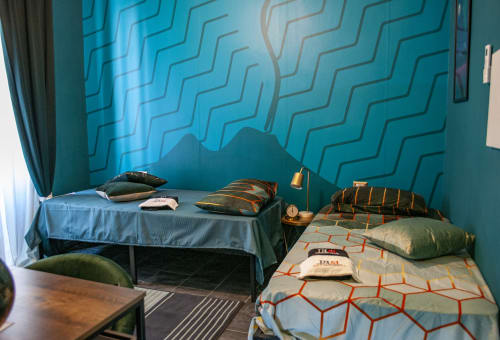 Vesuvio's Room at LH51 Naples features turquoise geometric walls, striped pillows, and modern furnishings with twin beds