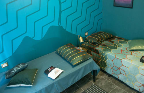Vesuvio's Room at LH51 Rooms and Apartments in Naples features twin beds with patterned quilts against a vibrant turquoise