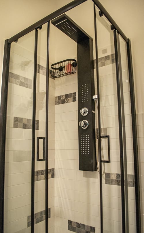 Modern black-framed shower enclosure with rainfall showerhead at LH51 Rooms in Naples