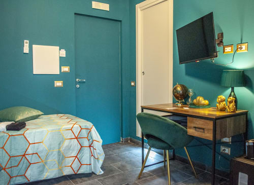 Modern turquoise bedroom at LH51 Naples with bed, desk, TV, and gold decorative accents