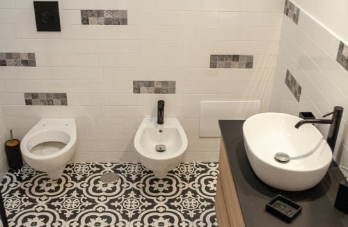 Moderno bagno presso LH51 Rooms a Napoli con sanitari bianchi, dettagli decorativi in piastrelle e pavimento a motivi