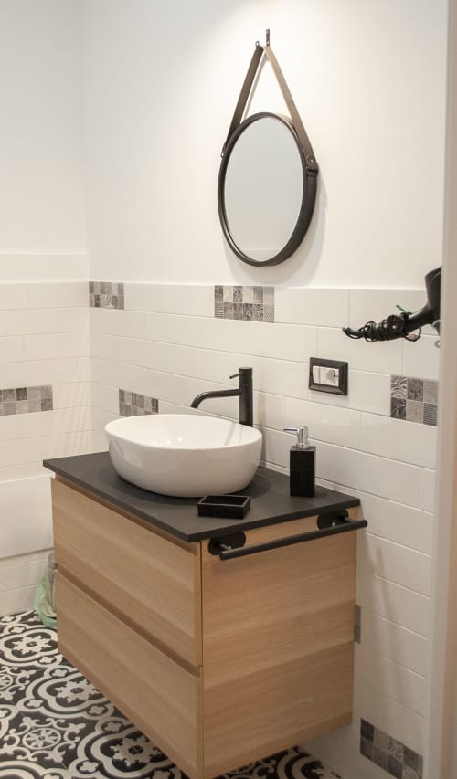 Vanità moderna con lavandino bianco e rubinetto nero, mobile in legno, specchio rotondo con cinghia in pelle presso LH51 Rooms