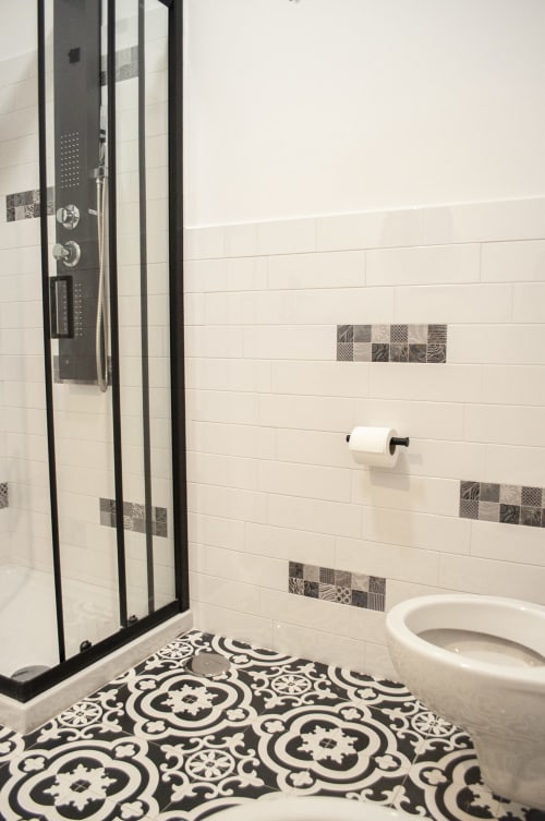 Bagno moderno presso LH51 Rooms a Napoli con piastrelle bianche a spina di pesce, doccia con cornice nera, dettagli decorativi in mosaico