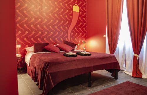 Luxurious red bedroom at LH51 Rooms, Naples - burgundy bed with pillows, patterned wallpaper, elegant drapes