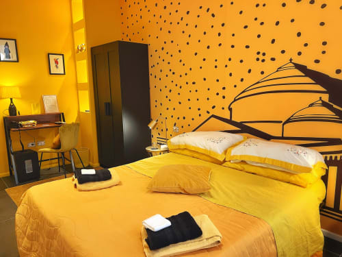 Camera luminosa giallo acceso alle LH51 Rooms di Napoli con pareti a pois, mobili neri e biancheria stratificata