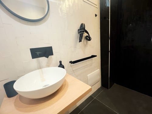 Bagno moderno della LH51 Rooms a Napoli con lavabo bianco su mobile in legno, pavimento in piastrelle nere e accessori contemporanei