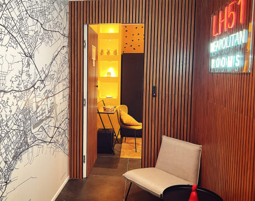 LH51 Rooms entrance in Naples with modern corridor, yellow-lit capsule room, and neon sign