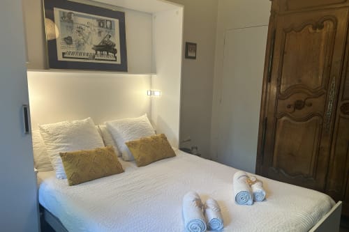 Chambre douillet aux Chambres Mes Oasis à Villers-lès-Nancy avec literie blanche, coussins dorés, tableaux encadrés, boiserie