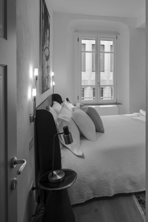 Chambre d'hôtel minimaliste au Palazzo Garibaldi Parma avec lit, oreillers, fenêtre et luminaires modernes