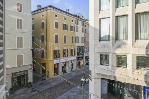 Palazzo Garibaldi à Parme surplombe une piazza historique italienne aux façades ocre jaune et commerces modernes au rez-de-chaussée