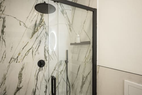 Robinetterie de douche noire moderne avec pluie de tête dans salle de bains carrelée en marbre, chambre hôtel Palazzo Garibaldi Parma