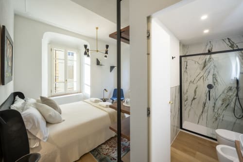 Chambre moderne du Palazzo Garibaldi Parma avec lit, salle de bain attenante avec douche en marbre et lumière naturelle abondante