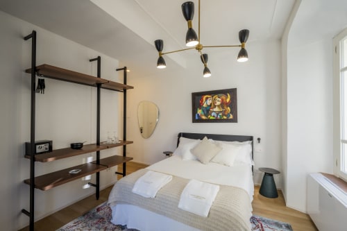 Camera moderna a Palazzo Garibaldi Parma con scaffalature in legno, lampade a sospensione nere e arte contemporanea sopra il letto