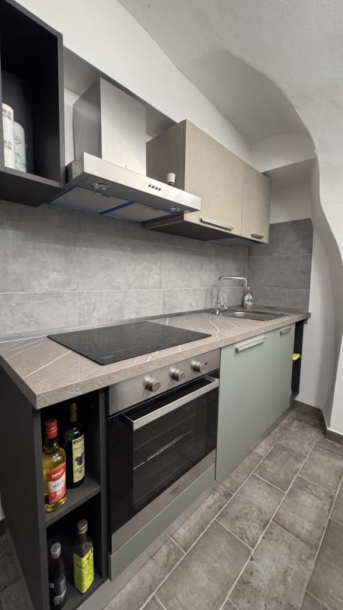 Cucina moderna nell'appartamento di Dolceacqua con fornello, lavandino, rivestimento in piastrelle grigie e mobili scuri