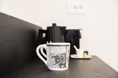 Tasse blanche avec plan de ville sur bureau dans une chambre de l'hôtel Palazzo Garibaldi de Parme, meublée de bois foncé