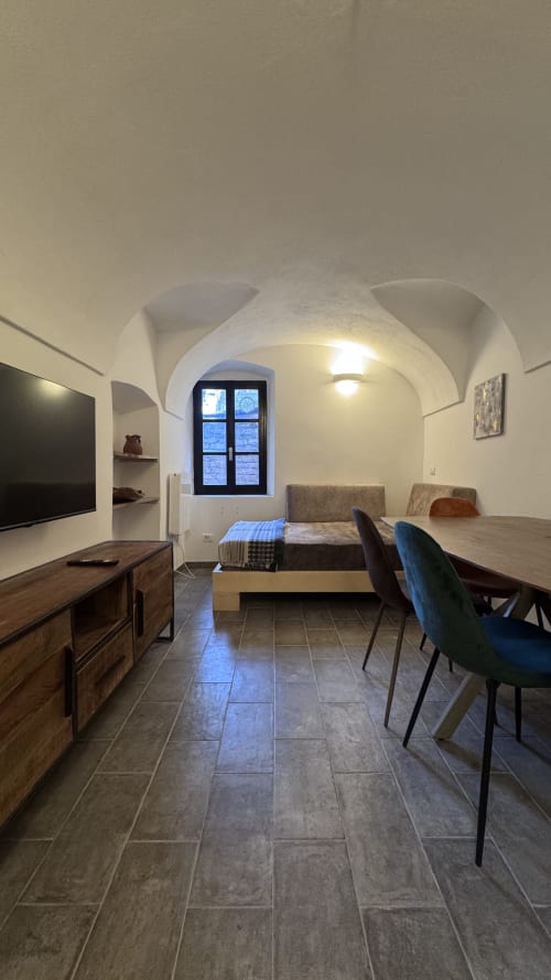 Moderno soggiorno dell'appartamento a Dolceacqua con soffitti ad arco, tavolo da pranzo, TV e finestra con vista sulla città presso The Residence by