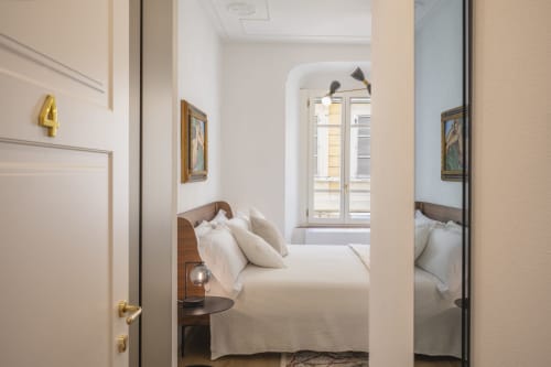 Chambre élégante au Palazzo Garibaldi Parma avec lits jumeaux, têtes de lit en bois et baie vitrée par arcades.