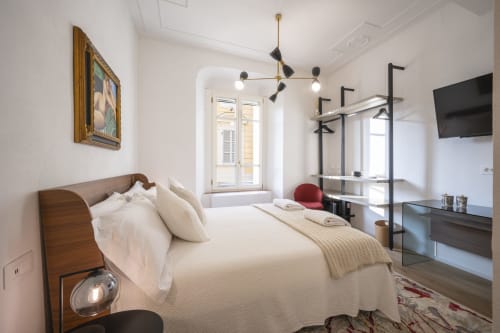 Chambre moderne de l'hôtel Palazzo Garibaldi Parma avec lit en bois, éclairage suspendu et mobilier contemporain