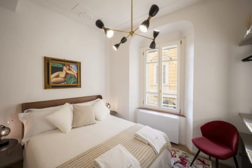 Chambre élégante du Palazzo Garibaldi Parma avec literie crème, tête de lit bois foncé, luminaires suspendus et fenêtres