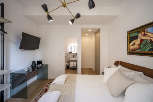 Chambre d'hôtel moderne du Palazzo Garibaldi Parma avec lit, TV, salle de bain attenante et luminaires contemporains