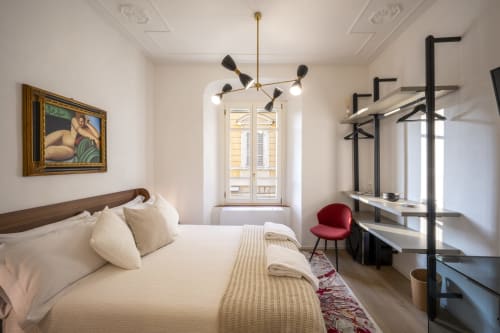 Chambre élégante du Palazzo Garibaldi Parma avec lit, luminaire suspendu moderne et étagères noires près de la fenêtre