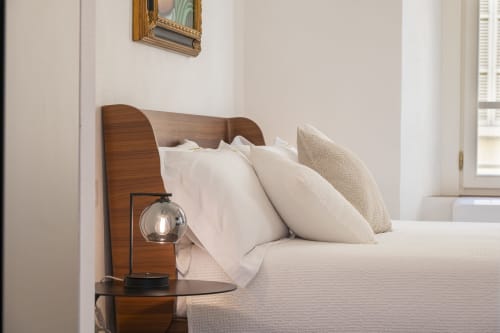 Chambre d'hôtel moderne au Palazzo Garibaldi Parma avec tête de lit en bois, oreillers blancs et lampe de chevet