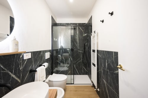 Salle de bain contemporaine du Palazzo Garibaldi Parma avec carrelage en marbre noir, douche à l'italienne et finitions en bois